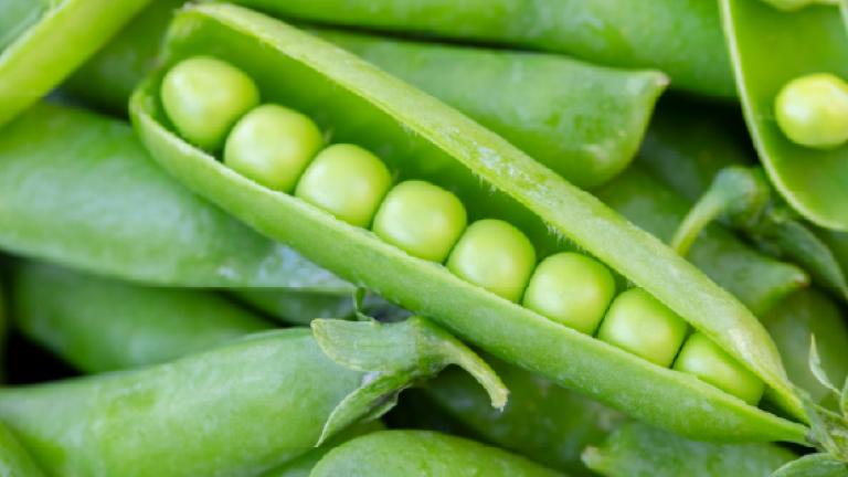 Vainas de guisantes verdes abiertas con guisantes en primer plano